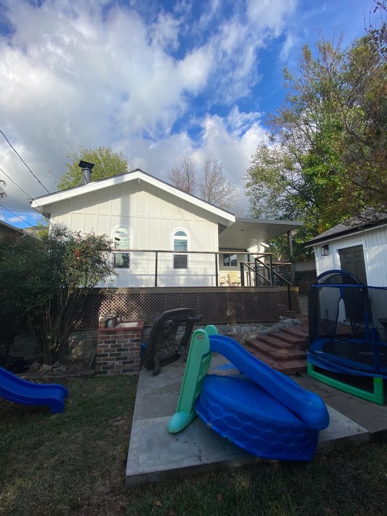 Backyard with raised deck, blue slide, trampoline, and stairs to house.